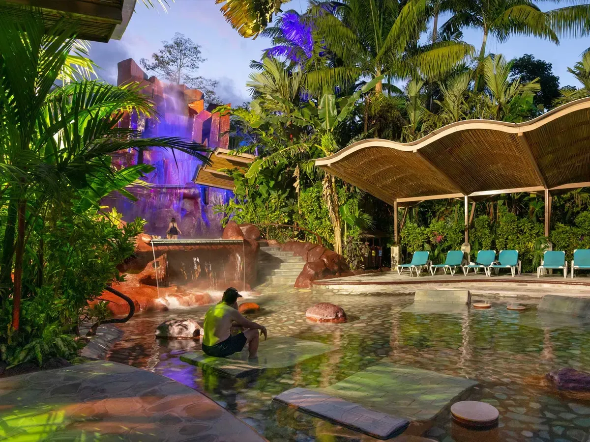 Thermal pools and a lit rock waterfall at Baldi, one of the hot springs in La Fortuna, Costa Rica